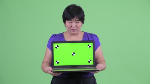 Felice giovane in sovrappeso donna asiatica pensando mentre mostra laptop — Video Stock