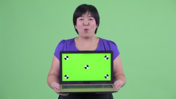 Szczęśliwy młody nadwaga Asian kobieta rozmowa podczas pokazywanie laptop — Wideo stockowe