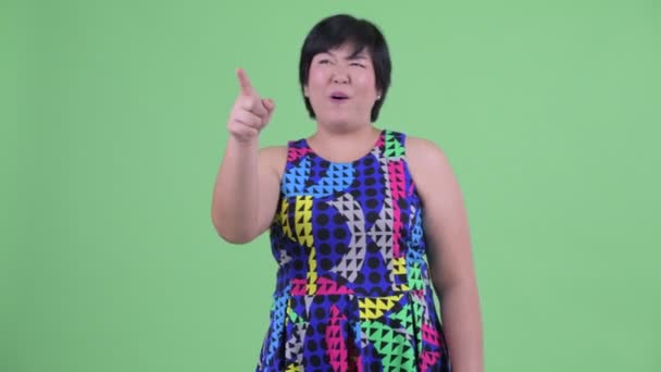 Happy young overweight Asian woman pointing finger ready to party — Stock Video