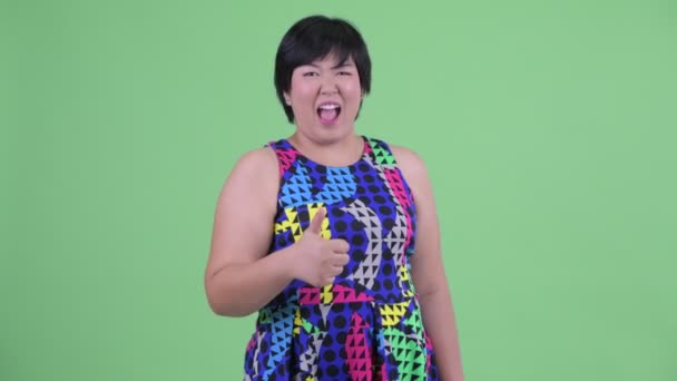 興奮した若い太りすぎのアジアの女性は、パーティーの準備ができて親指を与える — ストック動画