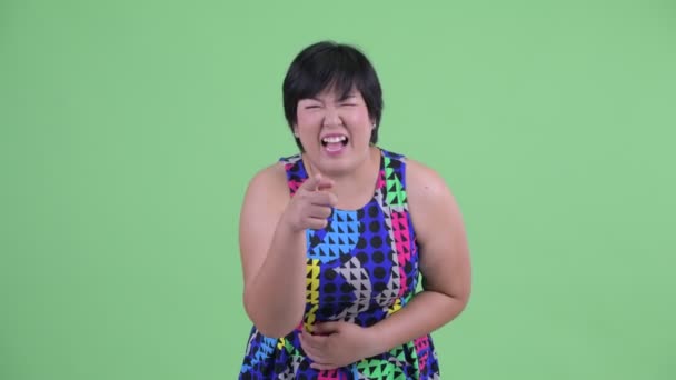 Happy young overweight Asian woman laughing and pointing at camera ready to party — Stock Video