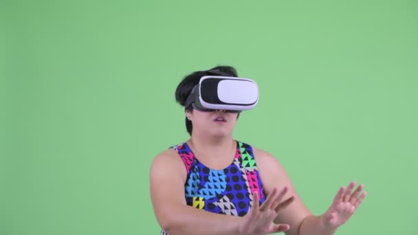 面对快乐的年轻超重亚洲妇女使用虚拟现实耳机和看起来惊讶 — 图库视频影像