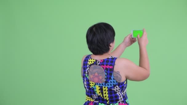 Vista trasera de la joven mujer asiática con sobrepeso tomando fotos con el teléfono — Vídeos de Stock
