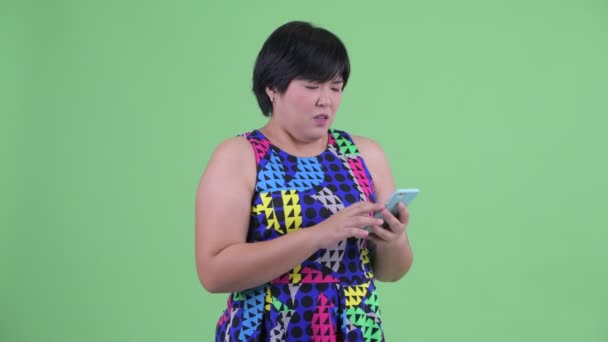 Gestresste junge übergewichtige Asiatin telefoniert und bekommt schlechte Nachrichten — Stockvideo