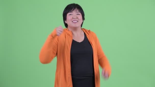 Щаслива молода надмірна вага Азіатська жінка дає великі пальці готові для тренажерного залу — стокове відео
