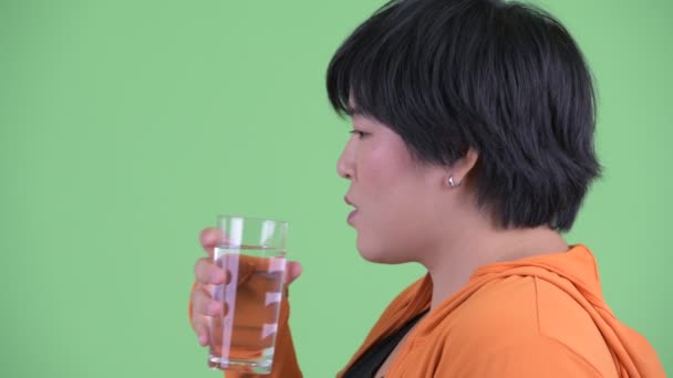 ジムの準備ができて水を飲む幸せな若い太りすぎアジアの女性のクローズアッププロファイルビュー — ストック動画
