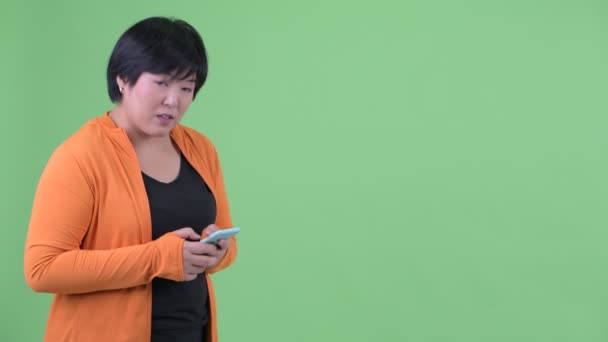 Lycklig ung övervikt asiatisk kvinna väntar när du använder telefonen redo för gym — Stockvideo