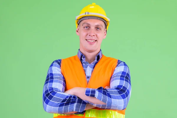 Happy young man construction worker smiling with arms crossed — Stock Photo, Image