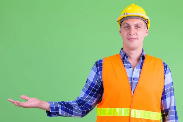 Portrait of young man construction worker showing something — Stock Photo, Image