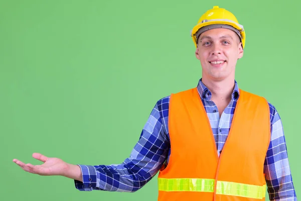 Happy young man construction worker showing something — Stock Photo, Image