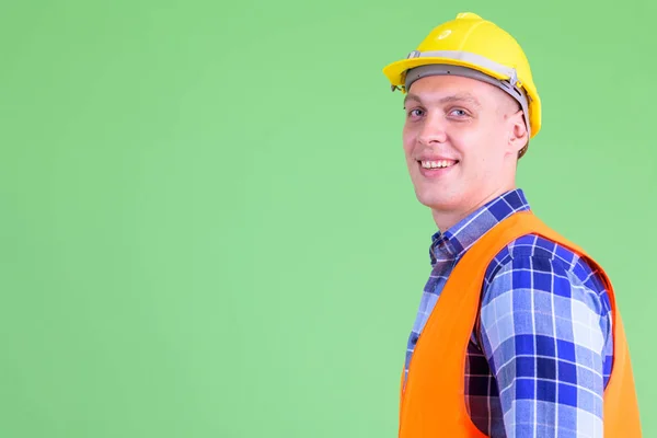 Крупним планом вид з профілю щасливого молодого працівника будівництва, дивлячись на камеру — стокове фото