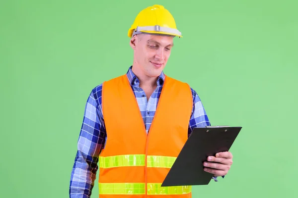 Young man construction worker reading on clipboard — Stock Photo, Image