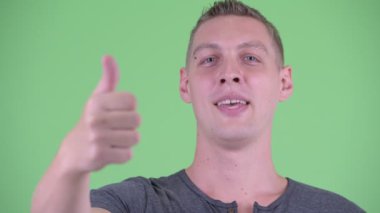 Mutlu genç adamın yüzü başparmak veren