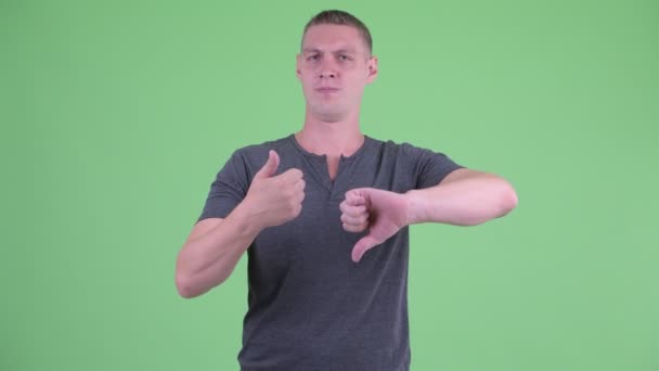 Verwarde jonge man kiezen tussen thumbs up en Thumbs Down — Stockvideo