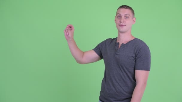 Porträt eines glücklichen jungen Mannes, der mit den Fingern schnippt und etwas zeigt — Stockvideo