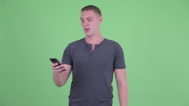 Наголошений молодий чоловік використовує телефон і отримує погані новини — стокове відео