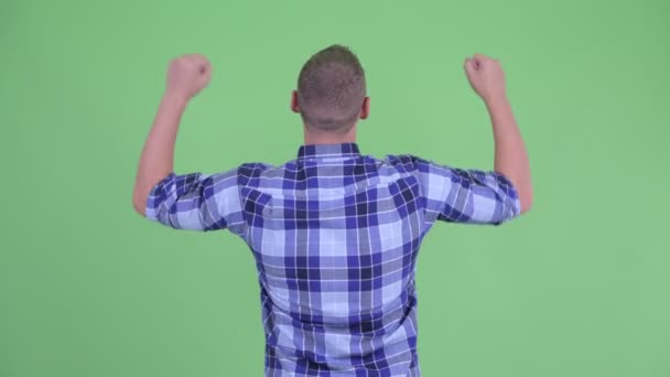 Vista trasera del joven hipster feliz con los puños levantados — Vídeos de Stock