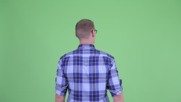 何かに触れる若いヒップスターの男の背面図 — ストック動画