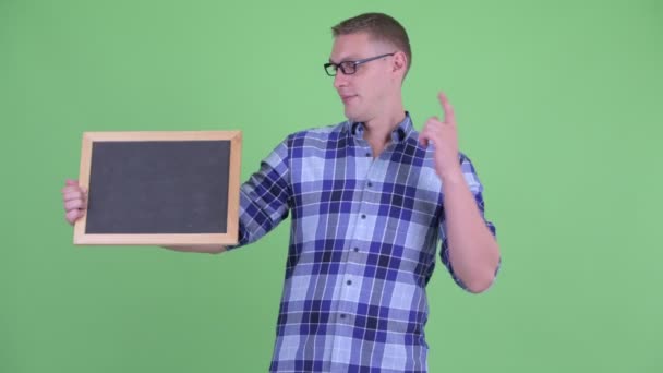 Lycklig ung hipster man håller Blackboard och ger tummen upp — Stockvideo