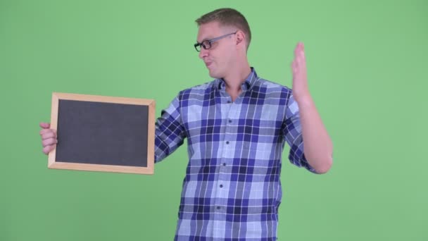 Stressad ung hipster man håller Blackboard och ger tummen ner — Stockvideo