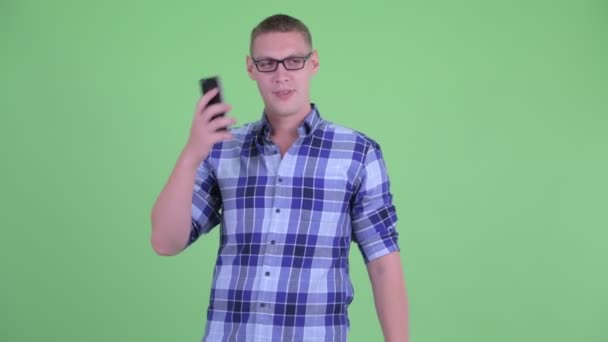 Lycklig ung hipster man multitasking och använda två telefoner — Stockvideo