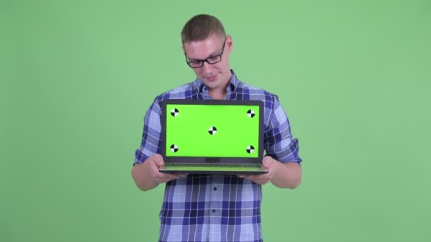 Gelukkig jonge hipster man denken terwijl het tonen van laptop — Stockvideo