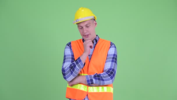 Benadrukte jonge man bouwvakker denken en naar beneden kijken — Stockvideo