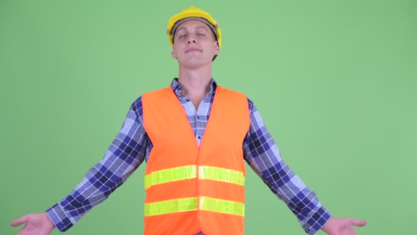 Счастливый молодой человек строитель расслабляется с закрытыми глазами — стоковое видео