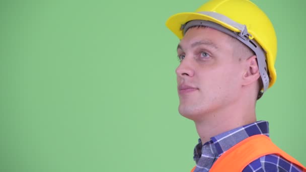 Vista del perfil del joven feliz trabajador de la construcción sonriendo — Vídeos de Stock