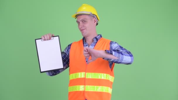 Stresli genç adam inşaat işçisi pano gösteren ve başparmak aşağı veren — Stok video