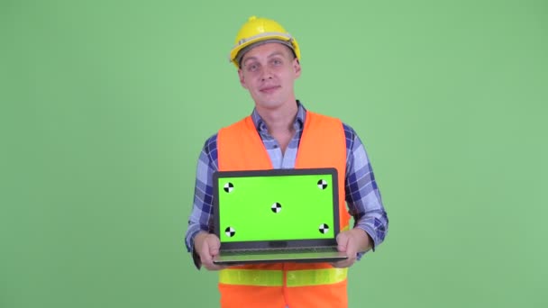 Lycklig ung man Construction arbetstagare tänkande när du visar laptop — Stockvideo