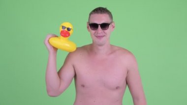 Mutlu gömleksiz genç adam lastik ördek partiye hazır