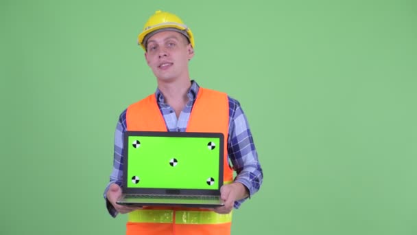 Lycklig ung man byggnadsarbetare pratar när du visar laptop — Stockvideo