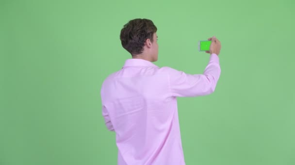 Visão traseira do jovem empresário tirando foto com telefone — Vídeo de Stock