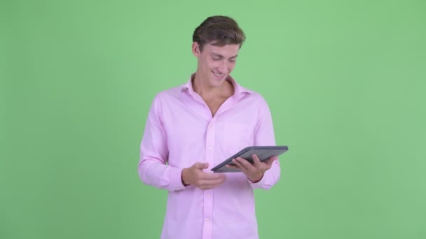 Щасливий молодий красивий бізнесмен думає під час використання цифрового планшета — стокове відео