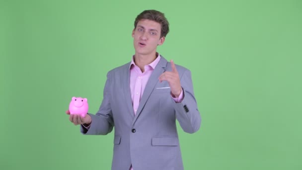 Boldog fiatal üzletember beszél, míg a gazdaságban malacka bank — Stock videók