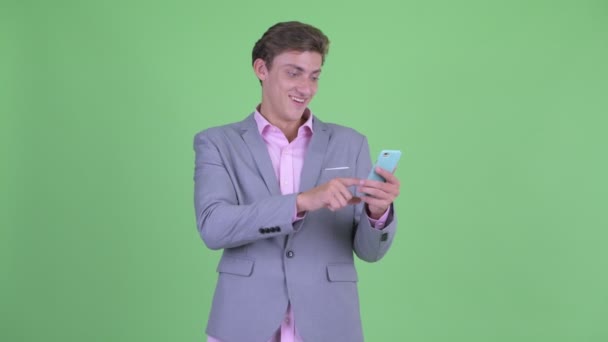 Feliz joven hombre de negocios usando el teléfono y recibiendo buenas noticias — Vídeos de Stock