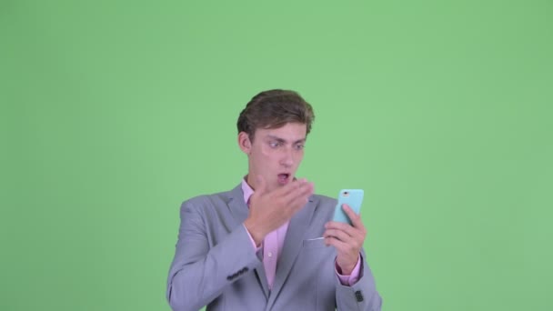 Face of young businessman using phone and looking shocked — Stock Video