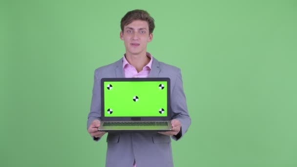 Щасливий молодий бізнесмен говорить, показуючи ноутбук — стокове відео