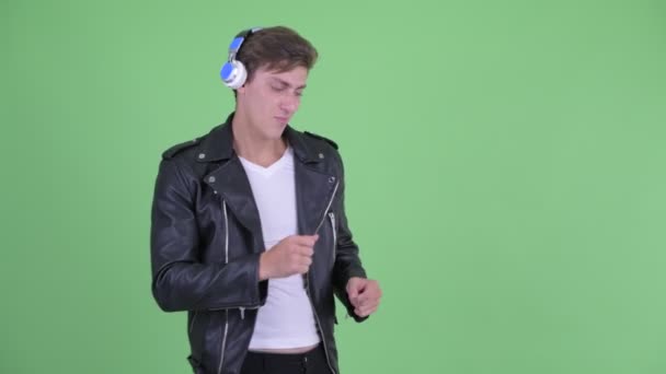 Šťastný mladý vzpurný muž, který poslouchá hudbu a tančí — Stock video