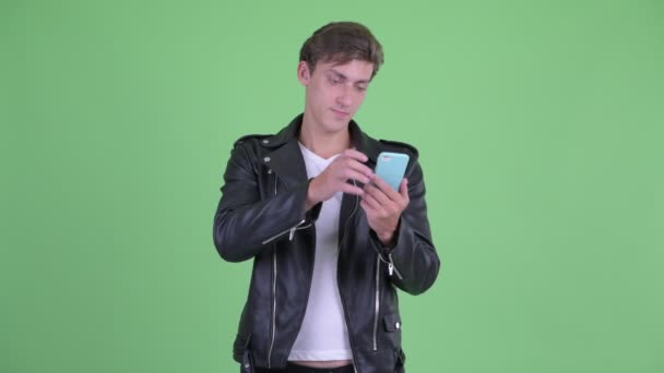 Šťastný mladý vzpurný muž přemýšleje při používání telefonu — Stock video