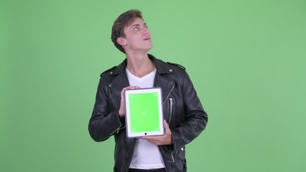 Mutlu genç asi adam dijital tablet gösterirken düşünme — Stok video