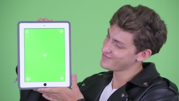 Visage de heureux jeune homme rebelle montrant tablette numérique — Video