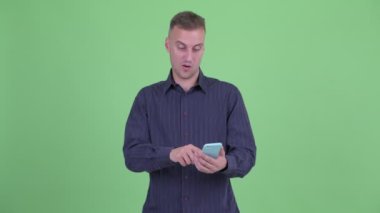 Mutlu yakışıklı işadamı telefon kullanarak ve iyi haber alıyorum