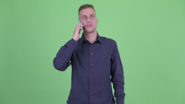 Gelukkig knappe zakenman denken en praten over de telefoon — Stockvideo