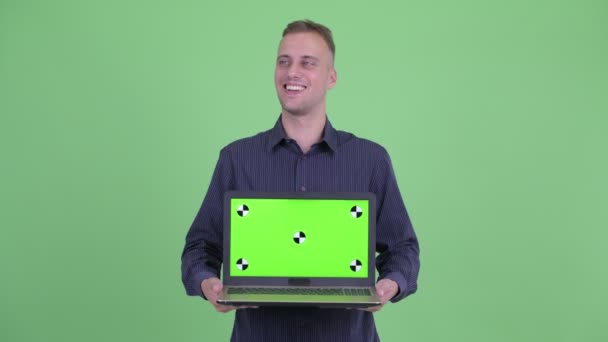 Bonito empresário feliz pensando ao mostrar laptop — Vídeo de Stock