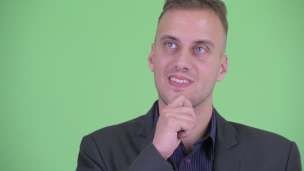 Face of happy handsome businessman in suit thinking and looking up — Stock Video