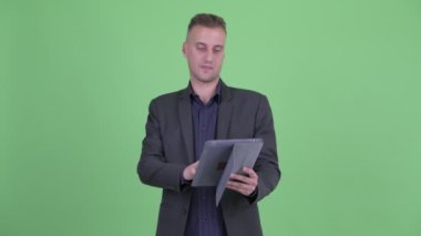 Dijital tablet kullanırken takım elbiseli mutlu yakışıklı işadamı düşünme