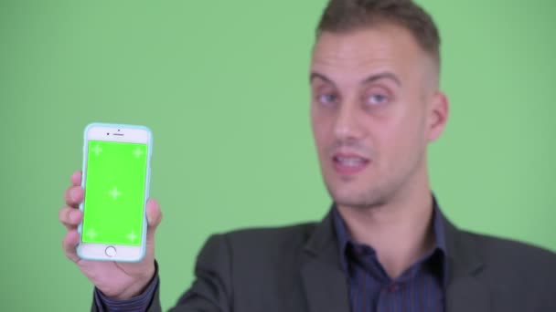 Face of Happy Handsome affärsman i kostym visar telefon — Stockvideo