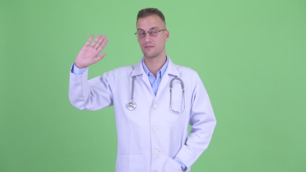 Happy handsome man doctor waving hand — Stock Video